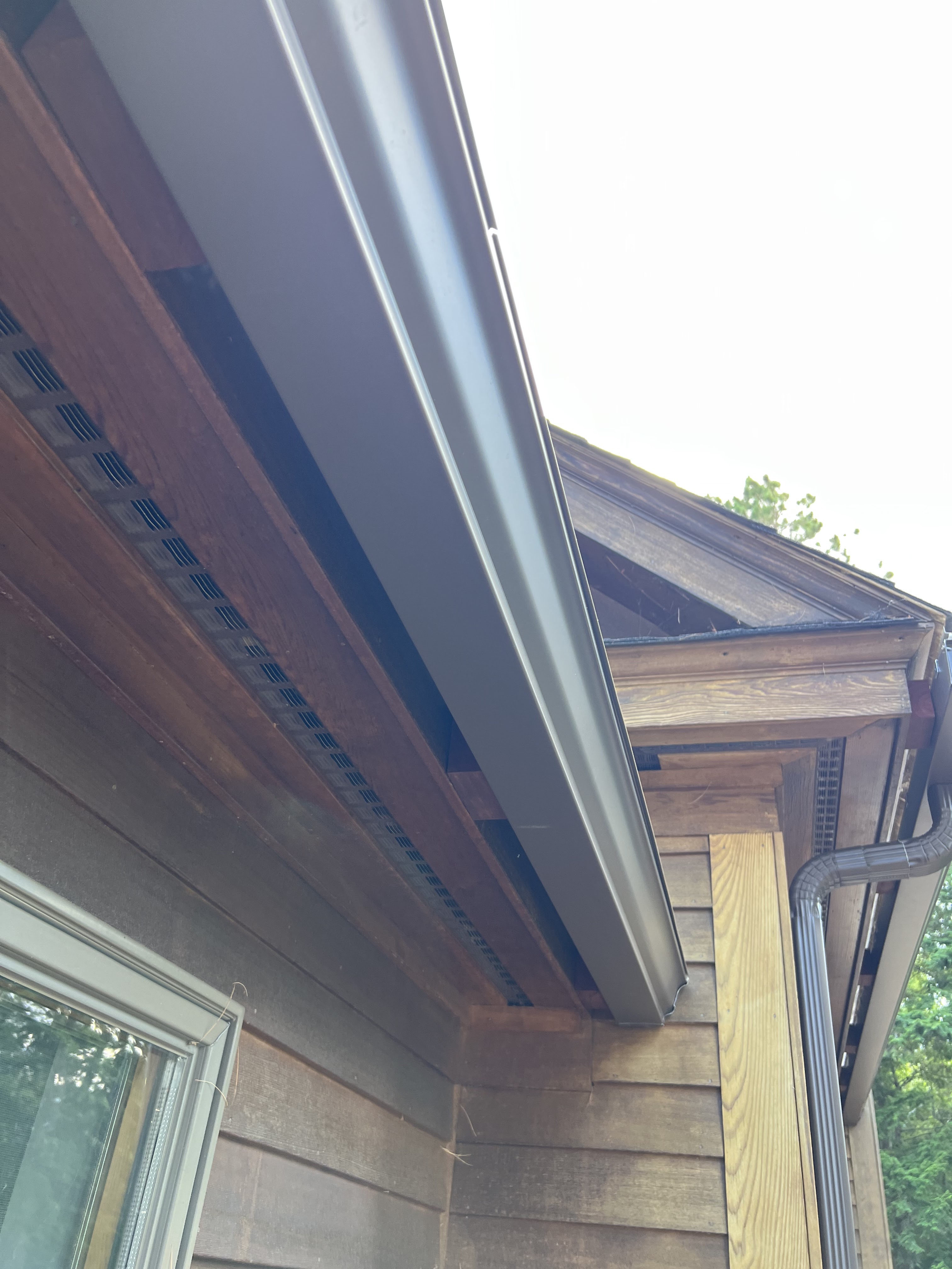 Musket brown seamless gutters installed on a cedar-sided New England home